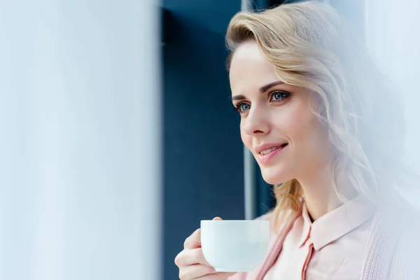 Seitenansicht einer nachdenklichen Frau mit einer Tasse Kaffee, die wegschaut — Stockfoto