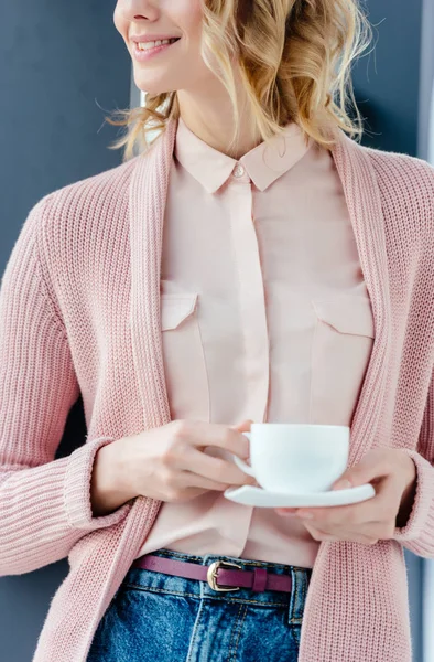 Tiro recortado de mulher sorridente em blusa rosa com xícara aromática de café nas mãos — Fotografia de Stock
