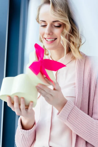 Happy woman opening heart shaped gift box in hands, mothers day holiday concept — Stock Photo