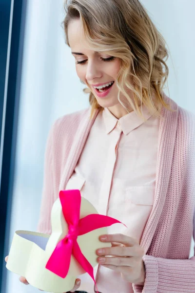 Heureuse femme ouvrant boîte cadeau en forme de coeur dans les mains, concept de vacances fête des mères — Photo de stock