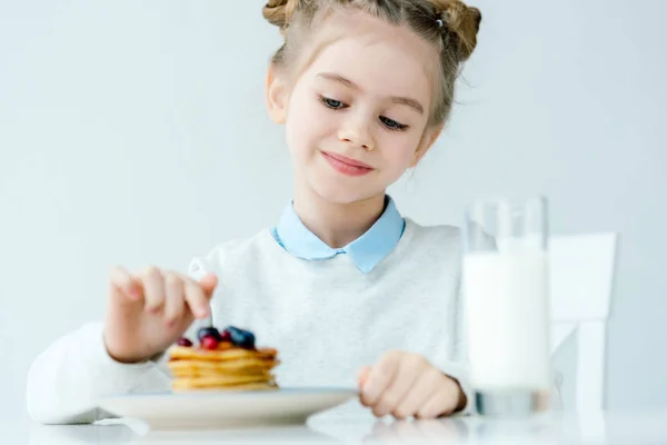 Selective focus of little kid looking at homemade pancakes with berries and honey on table — Stock Photo