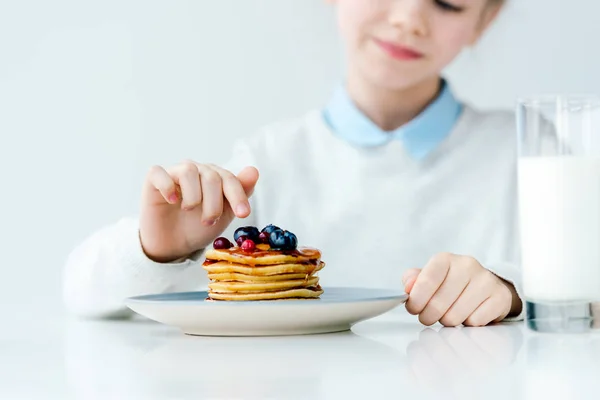 Selective focus of little kid looking at homemade pancakes with berries and honey on table — Stock Photo