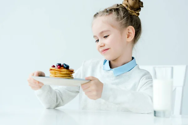 Little kid looking at homemade pancakes with berries and honey in hands — Stock Photo