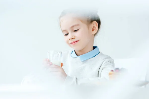 Foco seletivo da criança sorrindo bonito olhando para o vidro de leite nas mãos — Fotografia de Stock