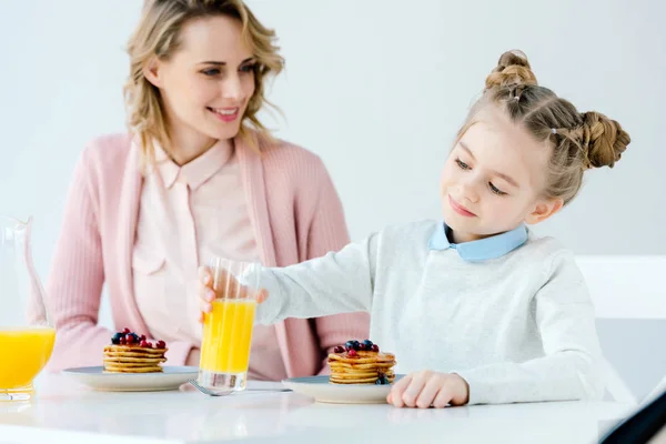 Lächelnde Mutter und Tochter beim gemeinsamen Frühstück am Tisch — Stockfoto