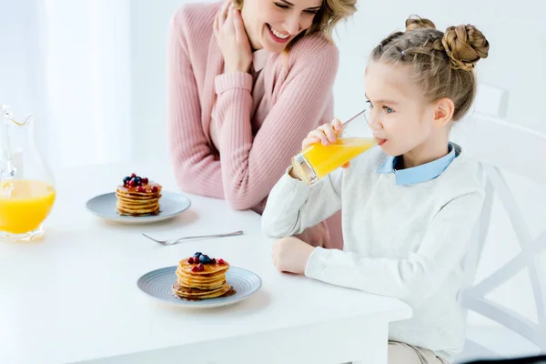 Mère et fille souriantes déjeunant ensemble à table — Photo de stock