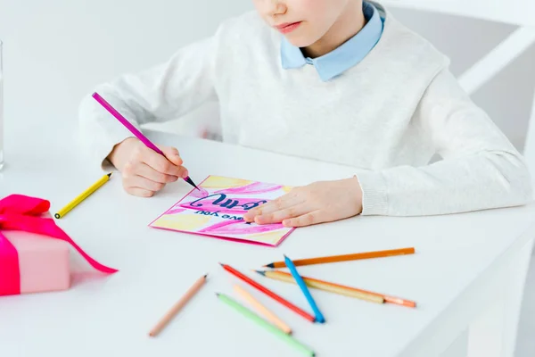 Cropped shot of kid drawing greeting postcard for mother with colorful pencils at table, mothers day holiday concept — Stock Photo