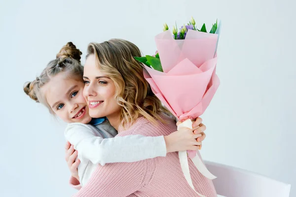 Portrait of smiling daughter with bouquet of flowers and happy mother hugging each other, happy mothers day concept — Stock Photo