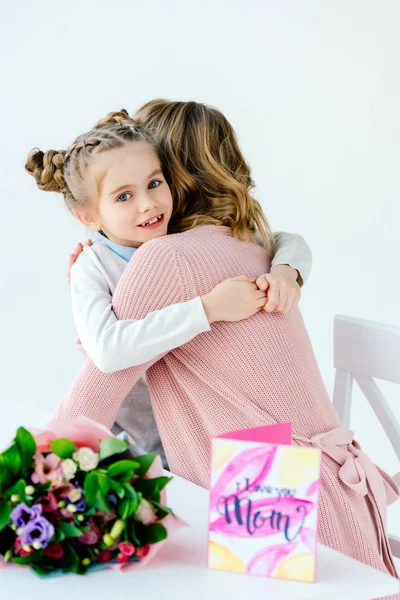 Niño y madre abrazándose unos a otros con regalos en la mesa, concepto de vacaciones del día de las madres - foto de stock
