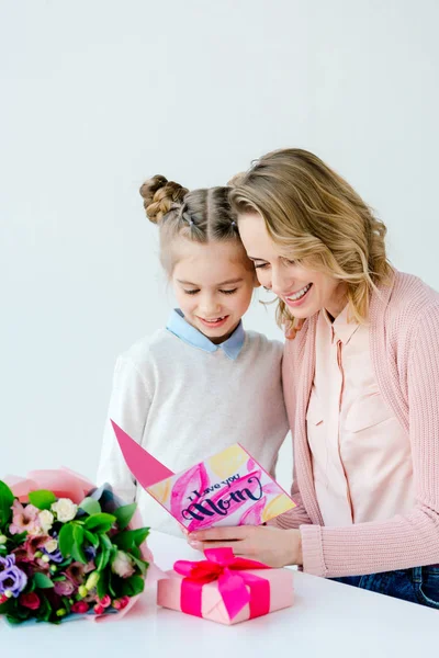Cheerful mother and daughter reading i love you mom greeting postcard together, mothers day concept — Stock Photo