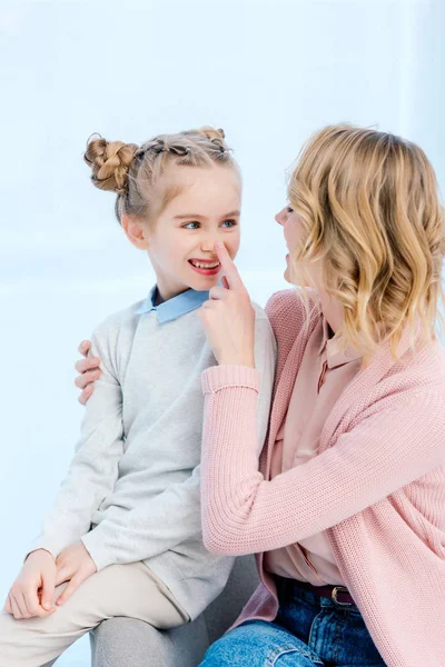 Mother touching smiling daughter nose with finger at home — Stock Photo