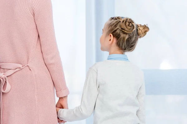 Immagine ritagliata di madre e figlia che si tengono per mano a casa — Foto stock