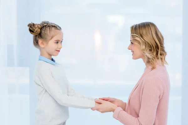 Side view of mother and daughter holding hands at home — Stock Photo