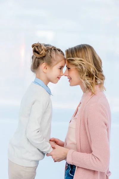 Visão lateral da mãe e da filha tocando com as testas em casa — Fotografia de Stock