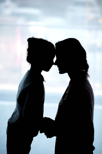 Silhouettes of mother and daughter touching with foreheads at home — Stock Photo