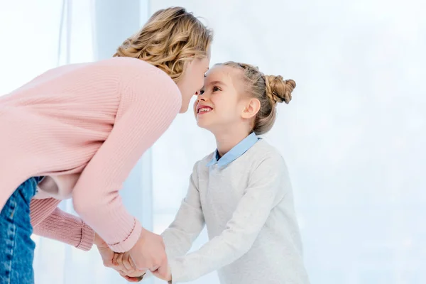 Mother and daughter holding hands and touching with noses at home — Stock Photo