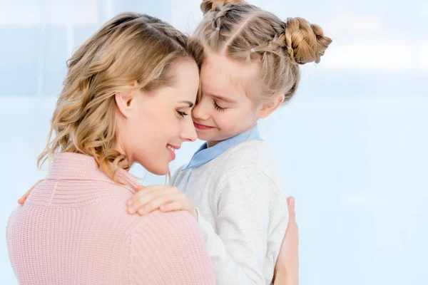 Lächelnde Mutter umarmt Tochter zu Hause — Stockfoto
