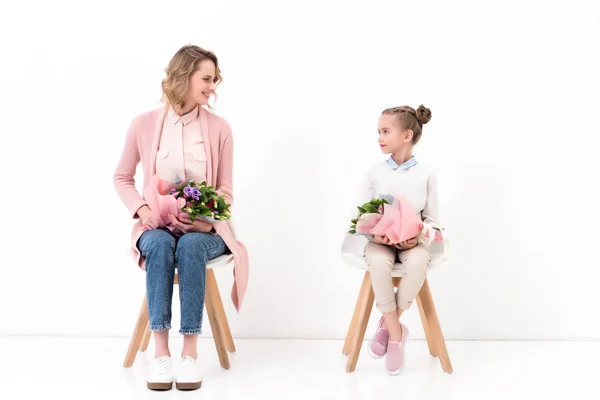 Mother and daughter sitting on chairs with bouquets of flowers, happy mothers day concept — Stock Photo