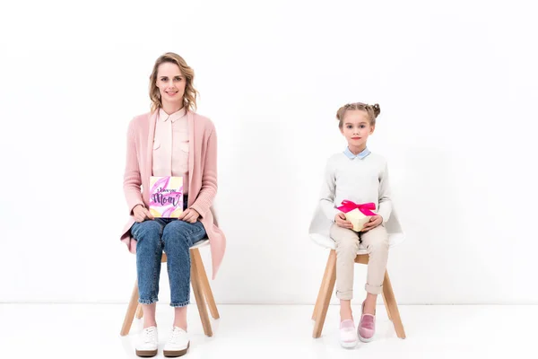 Mother and daughter sitting on chairs with postcard and bouquet, happy mothers day concept — Stock Photo