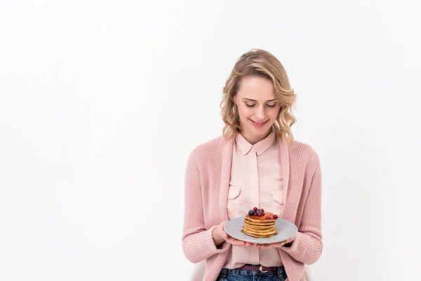 Schöne Frau sieht Pfannkuchen auf Teller isoliert auf weiß — Stockfoto