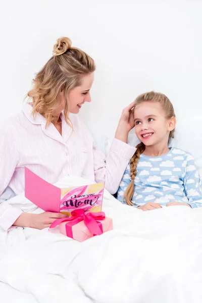 Mother palming smiling daughter and holding postcard on happy mothers day — Stock Photo