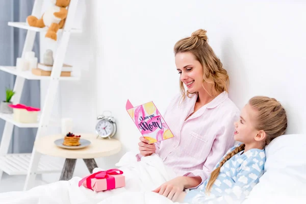 Счастливая мать читает дочери открытку на день счастливых матерей — стоковое фото