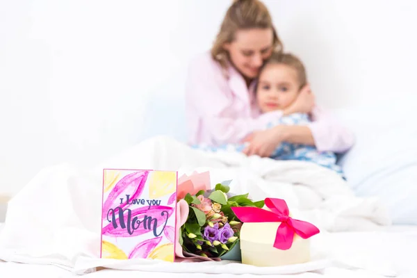 Madre e hija acostadas en la cama con regalos en primer plano, feliz concepto del día de las madres - foto de stock