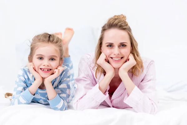 Mother and daughter resting chins on hands and looking at camera at home — Stock Photo