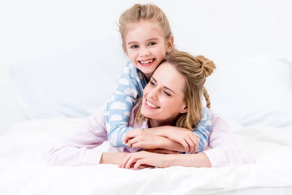 Filha feliz abraçando mãe na cama em casa — Fotografia de Stock