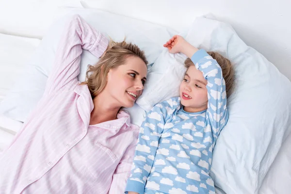 Vista ad alto angolo di madre e figlia felice sdraiato sul letto a casa — Foto stock