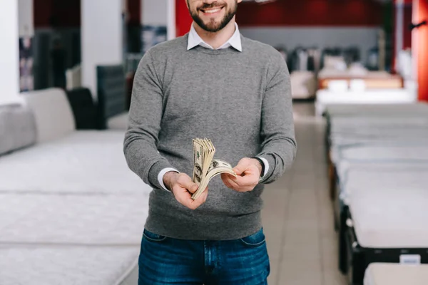 Обрізаний знімок усміхненого чоловіка покупця з доларовими банкнотами в магазині меблів — стокове фото