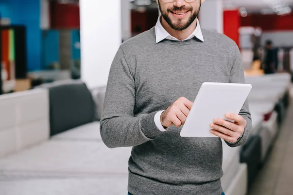 Cropped shot of man using digital tablet in furniture store with arranged mattresses — Stock Photo