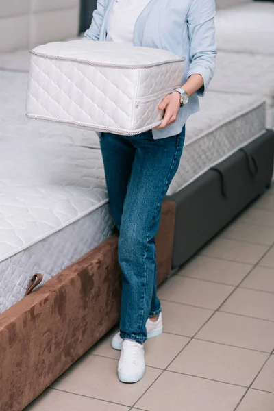 Cropped shot of woman with folding mattress in hands in furniture shop — Stock Photo