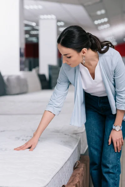 Porträt einer Frau, die orthopädische Matratzen im Möbelhaus berührt — Stockfoto