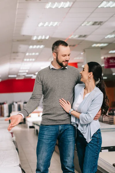 Smiling couple choosing mattress together in furniture shop — Stock Photo