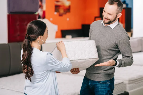 Couple choisissant matelas pliant ensemble dans le magasin de meubles avec matelas disposés — Photo de stock