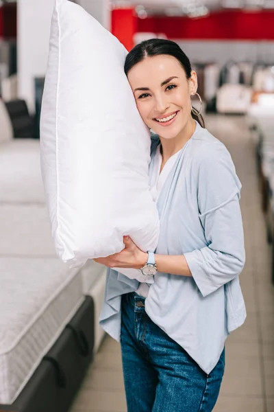 Портрет улыбающейся женщины с подушкой в мебельном магазине — стоковое фото
