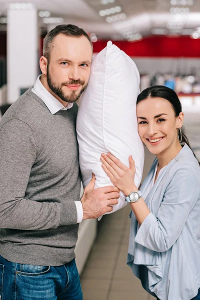 Retrato de pareja sonriente con almohada en tienda de muebles - foto de stock