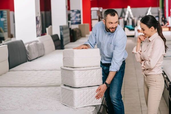 Couple avec matelas pliants dans le magasin de meubles avec matelas disposés — Photo de stock