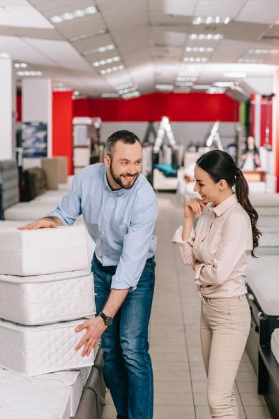 Couple with folding mattresses in furniture store with arranged mattresses — Stock Photo