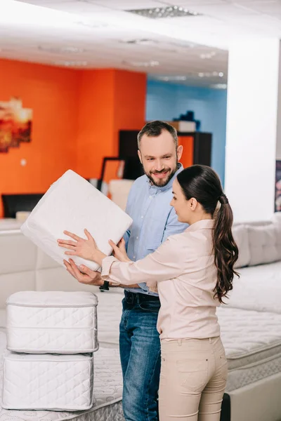 Couple choisissant matelas pliant ensemble dans le magasin de meubles avec matelas disposés — Photo de stock