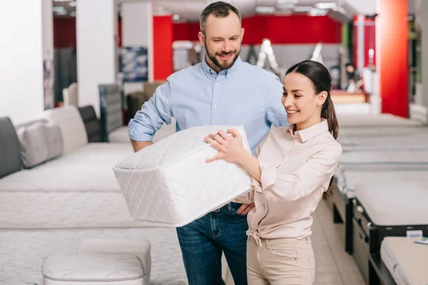 Couple choisissant matelas pliant ensemble dans le magasin de meubles avec matelas disposés — Photo de stock