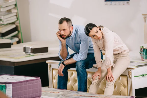 Portrait of bored couple in furniture store with arranged mattresses — Stock Photo