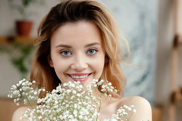 Retrato de bela jovem segurando flores brancas e sorrindo para a câmera — Fotografia de Stock