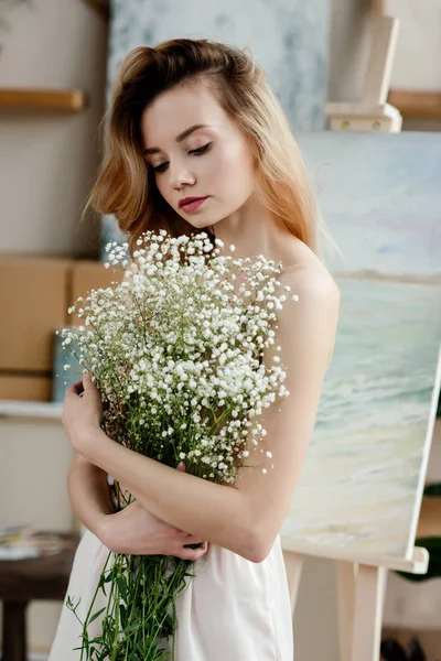 Bella ragazza tenera che tiene fiori bianchi in studio d'arte — Foto stock