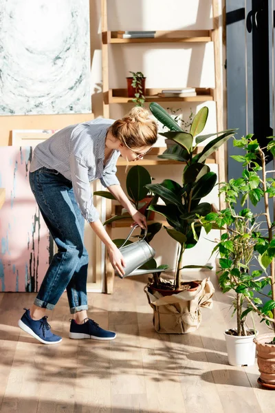 Jeune femme élégante dans les lunettes arrosage pot plan — Photo de stock