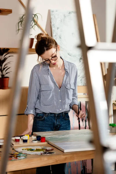 Giovane artista femminile elegante in occhiali da vista pittura — Foto stock