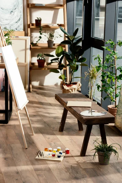 Интерьер мастерской художника с малярными принадлежностями, растениями в горшках и скамейкой — стоковое фото