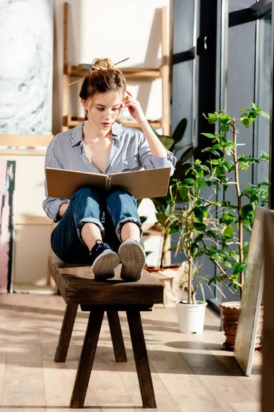 Jeune femme attrayante assise sur le banc et le livre de lecture — Photo de stock