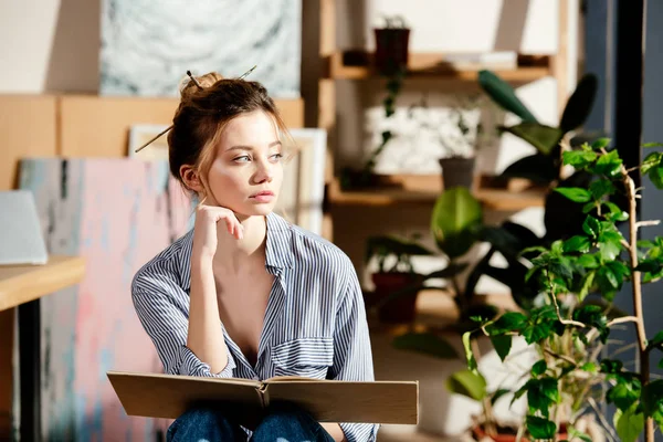 Portrait de jolie jeune femme assise avec livre — Photo de stock